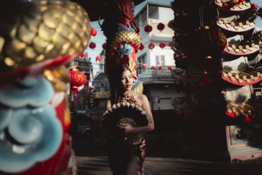 Geleneksel kostümlü ciddi bir Asyalı kadın. Kültür festivali için ayrıntılı bir başlığı var. Dramatik ışıkta performansa hazırlanan odaklanmış dansçı