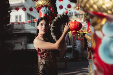 Geleneksel kırmızı Qipao 'daki güzel Asyalı kadın, Çin' de yeni yıl kutlamalarının tadını çıkartıyor, elinde nazik bir gülümsemeyle fener tutuyor. Neşe dolu kültür ve gelenek anı
