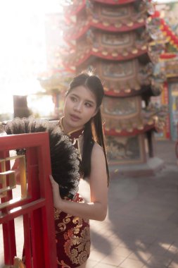 Şenlik kutlamaları sırasında tapınakta güzel kırmızı geleneksel Cheongsam elbiseli zarif Asyalı kadın. ruh hali huzurlu ve kültürel deneyim