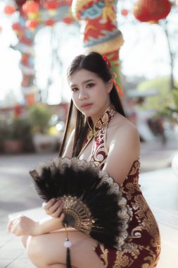 Kırmızı geleneksel Cheongsam 'lı güzel Asyalı kadın Çin Yeni Yılı' nı kutluyor. Festivaldeki kendine güvenen portresi modern zarafeti temsil ediyor.