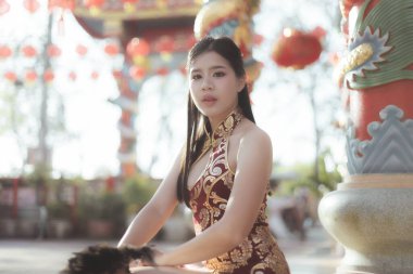 Geleneksel kırmızı Qipao 'lu Serene Asyalı kadın Çin' in yeni yılını tapınakta kutluyor. Kültür festivalinde kırmızı fener ve güzel geleneksel ortam yer alıyor