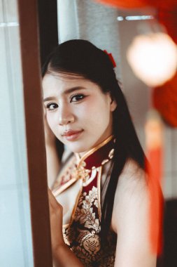 Ayın yeni yılını kutlayan, geleneksel Çin elbisesi giymiş, dingin, genç Asyalı kadın Qipao. Güzel bir kadın portresi. İçerde nazik bir ifade var.