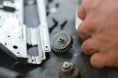 Karmaşık makineler için küçük metal dişlileri birleştiren yetenekli tamirci ellerini kapatın. Atölyede karmaşık tamir, teknoloji ve hassasiyet süreci