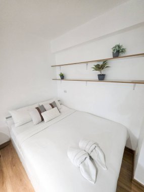Rahat yatak odası temiz beyaz yatak odası, modern minimalist tasarım ve bitkilerle dolu ahşap raf. Dinlenme, tatil ya da dinlenme için sakin ve dingin bir oda