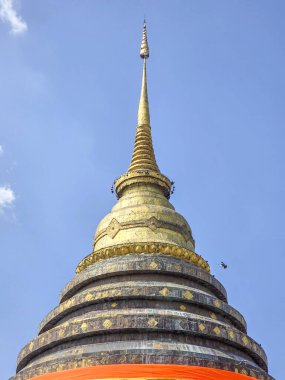 Tayland 'da eski bir tapınakta serene altın stupa. Görkemli Budist mimarisi temiz gökyüzüne, ruhani ve barışçıl inanç abidesine karşı duruyor.