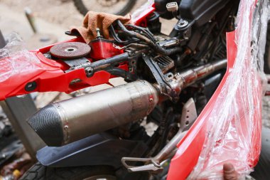 Atölyedeki zor tamirat sırasında motorsiklet egzozunu ve hasar gören alt iskeleti kapatın. kırmızı motosiklet özel yapım için kesme aracı ile bakım alıyor