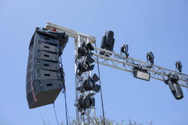 Profesyonel ses sistemi ve sahne aydınlatma ekipmanları bir açık hava konseri için metal kiriş üzerinde. Mavi gökyüzüne karşı güçlü hoparlör ve spot ışığı teçhizatı gösteri beklentisini uyandırıyor