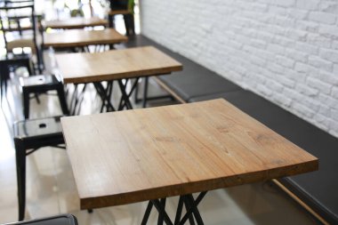 Ahşap masalar ve siyah sandalyelerle dolu sessiz ve boş bir kafe. Modern tasarım beyaz tuğla duvarlara karşı. Huzurlu ve sakin bir atmosfer yaratıyor. Etrafta kimse yok.