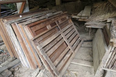 Terk edilmiş bir tavan arasında eski ahşap kapı panelleri ve kırsal panjurlar yığılmış. Yıpranmış kereste ve kereste tozlu, unutulmuş bir geçmiş ve nostaljik bir ruh hali yaratır.