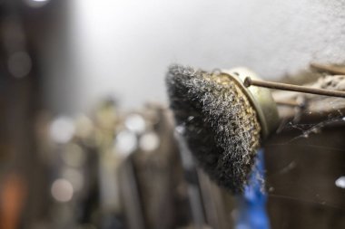 Bir endüstriyel atölyede metal öğütme ve temizleme gibi hareket halindeki elektrikli aletlerin üzerindeki tel fırçaları kapatın. Yoğun etki, sert yüzeydeki toz ve enkazı tekmeler.