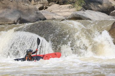 Maceraperest bir insan güneşli bir günde, açık hava su sporu etkinliği sırasında yoğun heyecan ve heyecan taşıyan büyük kayaların üzerinden hızla aşağı iniyor.