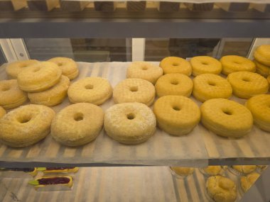 Fırın rafında nefis, sade çörekler sergileniyor. Kahvaltı ya da atıştırmalık lezzetli hamur işleri. Altın sarısı pişmiş yiyecekler yemek için hazır.