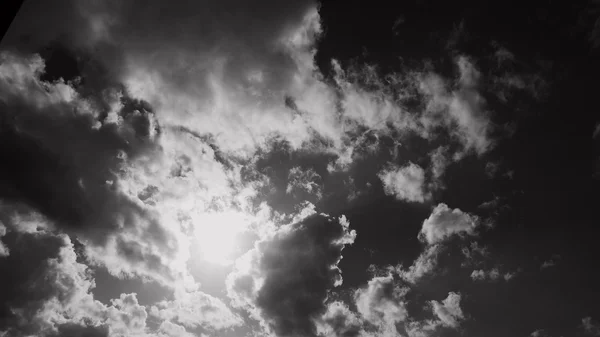 Dans le ciel, le soleil traverse les nuages. Noir et blanc ph — Photo