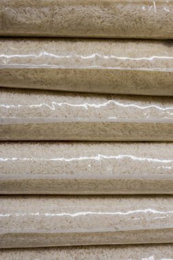 Plastik torbalar dolusu uzun taneli pirinç yığınlar halinde sergileniyor.