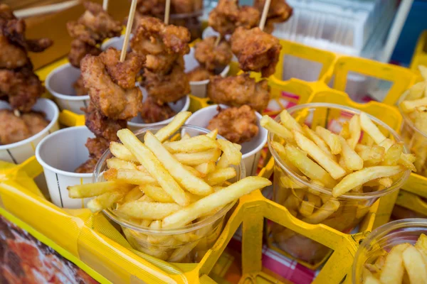 Potato fries and meat on sticks on sale — Stock Photo, Image