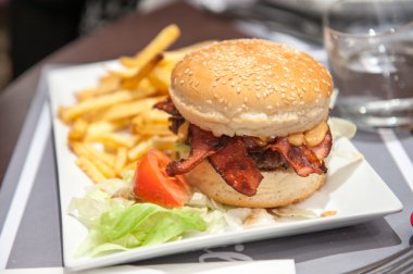 Pastırmalı çizburger ve patates kızartması bir plaka üzerinde kapat