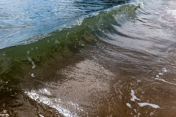 Golven als ze het zandstrand hit — Stockfoto