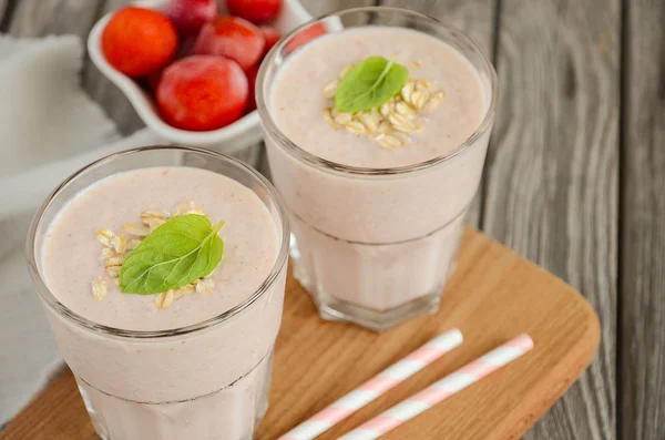 Batido de fresa y plátano con avena en la mesa rústica de madera . — Foto de Stock