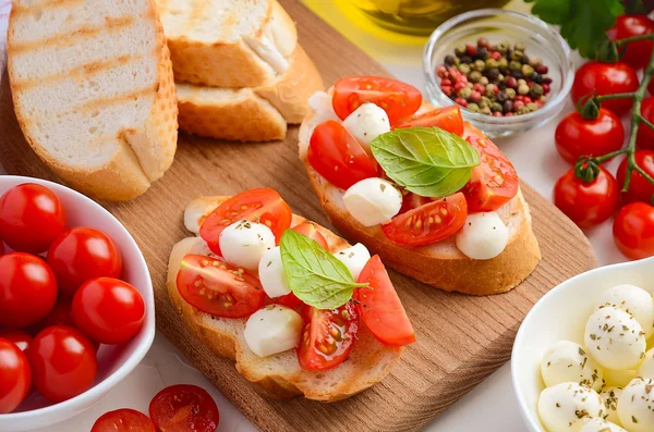 Bruschetta with cherry tomatoes and mozzarella on wooden board. — Stock Photo, Image