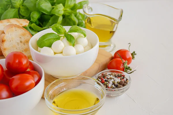 Italian food ingredients  mozzarella, tomatoes, basil and olive oil on rustic wooden background — Stock Photo, Image