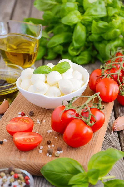 Italian food ingredients  mozzarella, tomatoes, basil and olive oil on rustic wooden background — Stock Photo, Image