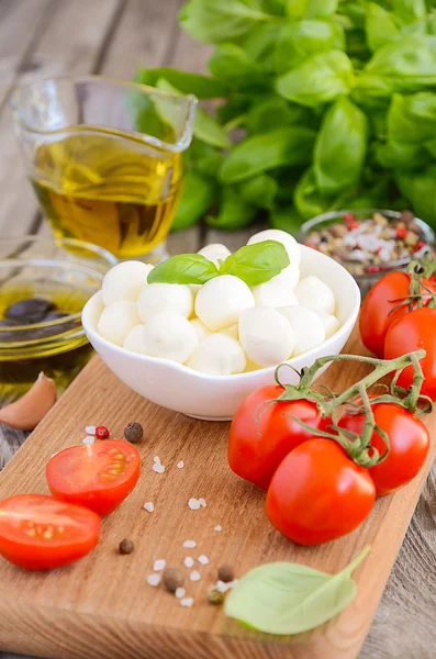 Italian food ingredients  mozzarella, tomatoes, basil and olive oil on rustic wooden background — Stock Photo, Image