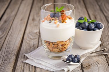 Tatlı ev yapımı granola, yoğurt ve rustik arka plan üzerinde yaban mersini ile