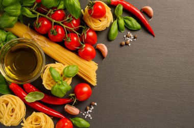 İtalyan yemekleri için siyah arka planda makarna, sebze, bitki ve baharat.