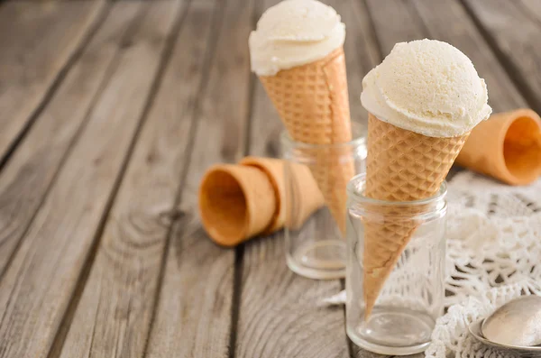 Sorvete de baunilha em cone de waffle em fundo de madeira rústica — Fotografia de Stock