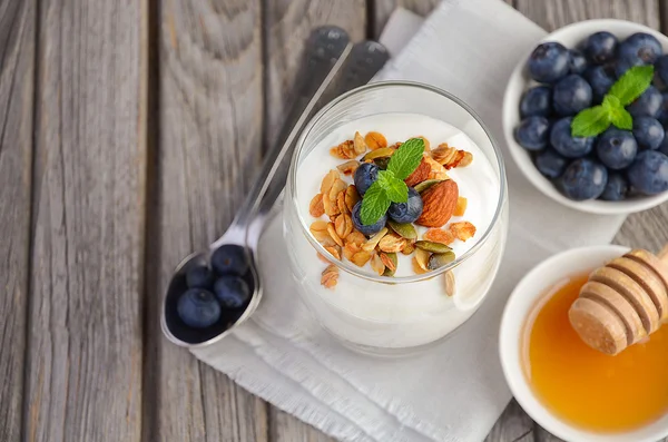 Hidangan penutup dengan granola buatan sendiri, yogurt dan blueberry dengan latar belakang pedesaan — Stok Foto