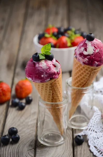 Helado con arándanos y fresas en cono de gofre sobre fondo rústico de madera — Foto de Stock