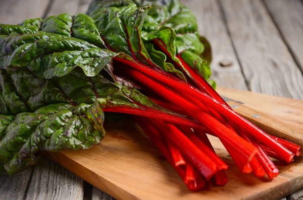 Frische rote Mangold-Blätter auf hölzernem Hintergrund — Stockfoto