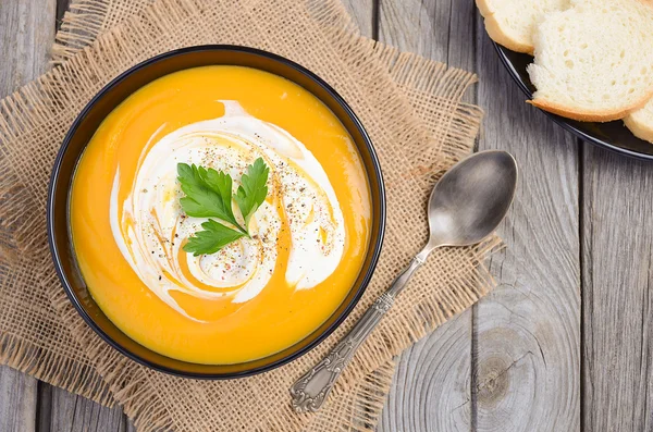 Kürbissuppe mit Sahne und Petersilie auf Holzgrund — Stockfoto