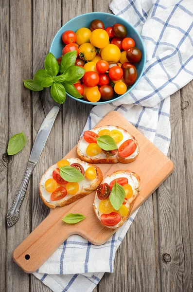 Bruschetta with feta cheese and cherry tomatoes on wooden background — Stock Photo, Image