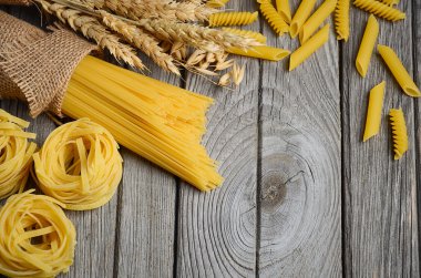 Pişmemiş makarna ve buğday rustik arka plan üzerinde