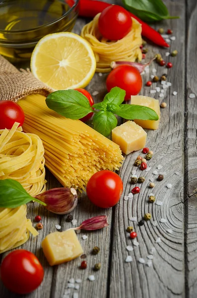 Pastas, verduras, hierbas y especias para la comida italiana en la mesa rústica de madera . —  Fotos de Stock