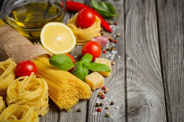 Pasta, Gemüse, Kräuter und Gewürze für italienische Küche auf dem rustikalen Holztisch. — Stockfoto