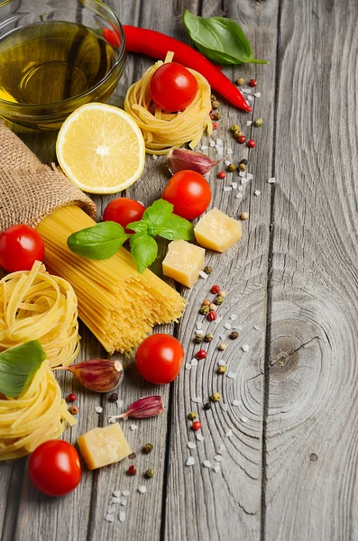 Pasta, Gemüse, Kräuter und Gewürze für italienische Küche auf dem rustikalen Holztisch. — Stockfoto
