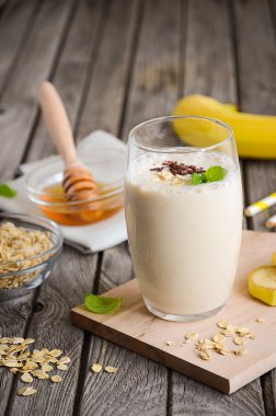 Muz smoothie rustik ahşap masa üzerinde yulaf ezmesi ile.