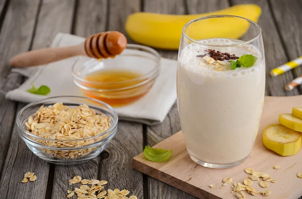 Batido de plátano con avena en la mesa rústica de madera . — Foto de Stock