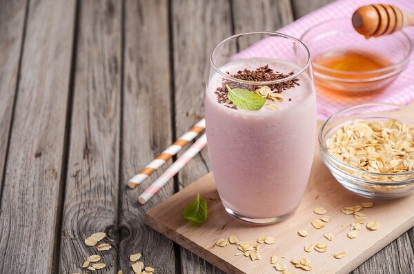 Strawberry and banana smoothie with oatmeal on the rustic wooden table.