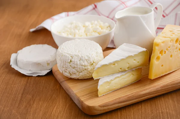 Produtos lácteos frescos. Leite, queijo, brie, camembert e queijo cottage no fundo de madeira . — Fotografia de Stock