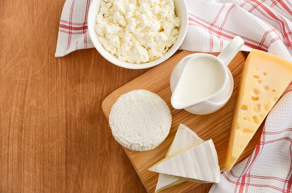 Productos lácteos frescos. Leche, queso, brie, camembert y requesón sobre fondo de madera . — Foto de Stock