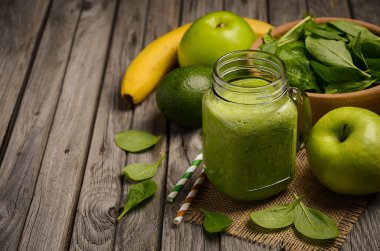 Elma, muz, avokado ve ıspanak ahşap rustik zemin üzerine yeşil smoothie.