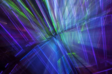 Yeşil, mor ve mavi ışık desenlerinin soyut bir görüntüsü.