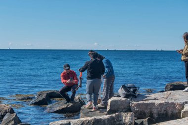 Groton, Connecticut. 25 Ekim 2025. Long Island 'daki Bluff Point Eyalet Parkı' nda yakalanan siyah balığın fotoğrafını çeken Çinli bir adam..