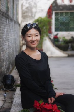 Mutlu bir Asyalı kadın Macau Çin 'deki tarihi Mandarin evinde kırmızı noktaların yanında oturuyor..