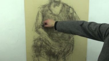 Drawing a fast sketch of old sitting woman with a charcoal stick