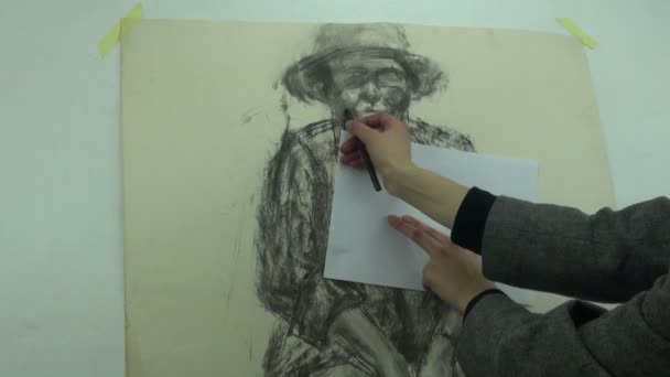Рисуем набросок женщины средних лет с помощью угольной палки, покрывая часть рисунка листом бумаги — стоковое видео
