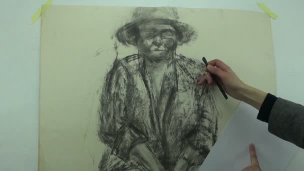 Drawing a fast sketch of a middle aged woman with a charcoal stick while covering part of drawing with a piece of paper — Stock Video